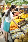 Chinesin wählt Früchte im Supermarkt — Stockfoto