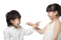 Asian children pointing at each other on white background — Stock Photo