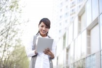 Chinese businesswoman using digital tablet in city — Stock Photo