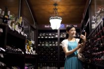 Mulher chinesa escolhendo vinho na adega — Fotografia de Stock