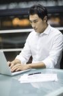 Homme d'affaires chinois travaillant avec un ordinateur portable au bureau — Photo de stock