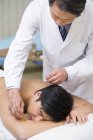 Médico chino senior que da acupuntura al paciente masculino - foto de stock
