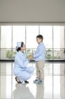 Китайская медсестра разговаривает с маленьким мальчиком в больнице — стоковое фото