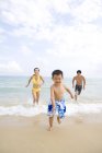 Pais perseguindo filho na praia do mar — Fotografia de Stock