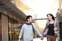 Chinese couple walking on street and holding hands — Stock Photo