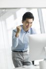 Empresário chinês aplaudindo com computador no escritório — Fotografia de Stock