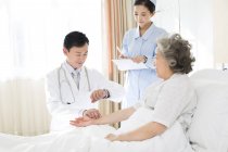 Chinese doctor taking pulse of patient in hospital — Stock Photo