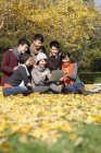 Chinese college students using laptop in campus park in autumn — Stock Photo