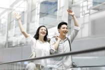Pareja china saludando en la escalera mecánica de la estación de metro - foto de stock