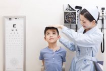 Enfermera china midiendo chico en sala de examen - foto de stock