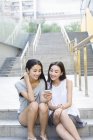 Chinesische Freundinnen hören Musik auf Straßentreppen — Stockfoto