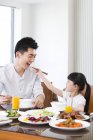 Китайський дочка годування батька з паличками для їжі під час обіду — стокове фото
