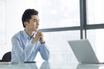 Китайський бізнесмен, сидячи руками, склала в офісі — стокове фото