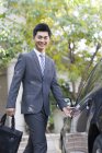 Молодой китайский бизнесмен открывает автомобильную дверь — стоковое фото