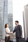 Empresarios chinos dando la mano en el distrito financiero - foto de stock