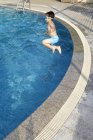 Маленький хлопчик в окулярах стрибає у воду в басейні — стокове фото