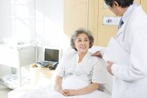 Chinese doctor talking with patient in hospital — Stock Photo