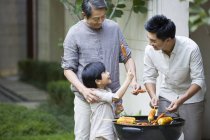 Chinese male multi-generation family barbecuing in courtyard — Stock Photo