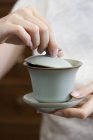 Close-up of female hands holding tea cup with lid — Stock Photo