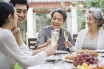 Chinese family toasting at dining table in courtyard — Stock Photo
