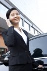 Chinese businesswoman talking on phone in front of car — Stock Photo