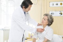 Médico chinês usando estetoscópio no paciente no hospital — Fotografia de Stock