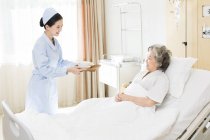 Infirmière chinoise servant de la nourriture pour les patients âgés — Photo de stock