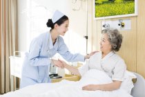 Chinese nurse taking care of senior woman in hospital — Stock Photo