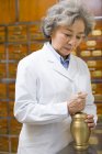 Médecin chinois senior broyage herbes médicinales — Photo de stock