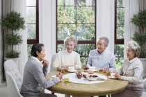 Senior Chinese friends eating together in dining room — Stock Photo