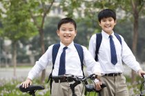 Écoliers chinois posant avec des vélos à l'extérieur — Photo de stock