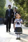Китайские родители идут со школьницей по улице — стоковое фото