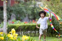 Pequeno menino chinês voando pipa no jardim — Fotografia de Stock