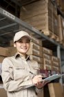 Female Chinese warehouse worker with clipboard — Stock Photo