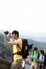 Китаец с биноклем смотрит на вид с друзьями на Великой Стене — стоковое фото