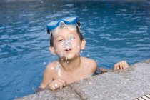 Chinese boy spitting water at poolside — Stock Photo