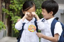 Chinese boy consoling crying girl with lollipop — Stock Photo
