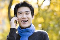 Jovem chinês falando no telefone no parque — Fotografia de Stock