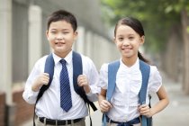 Compañeros alegres en uniforme escolar posando en la calle - foto de stock
