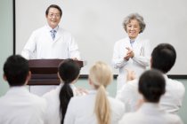 Trabajadores médicos chinos aplaudiendo en seminario - foto de stock
