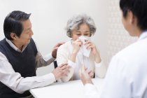 Chinese senior man consoling woman in hospital — Stock Photo