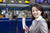 Chinese businesswoman holding ticket in airport — Stock Photo