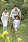 Família chinesa correndo e se divertindo no jardim — Fotografia de Stock