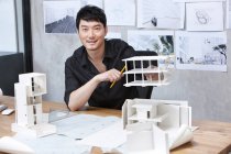 Chinesischer Architekt sitzt mit Architekturmodell — Stockfoto