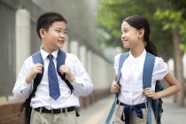 Fröhliche Mitschüler in Schuluniform posieren auf der Straße — Stockfoto