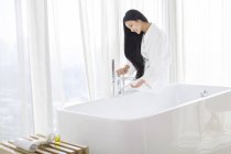 Mujer china llenando la bañera con agua - foto de stock