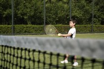 Little Chinese boy playing tennis at court — Stock Photo