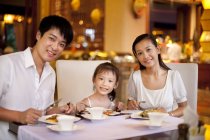 Genitori cinesi con figlia che pranzano nel ristorante — Foto stock