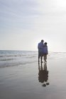 Coppia anziana a piedi lungo la spiaggia di mare — Foto stock