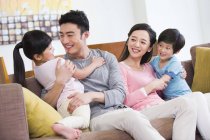Chinese family with two kids resting in sofa — Stock Photo